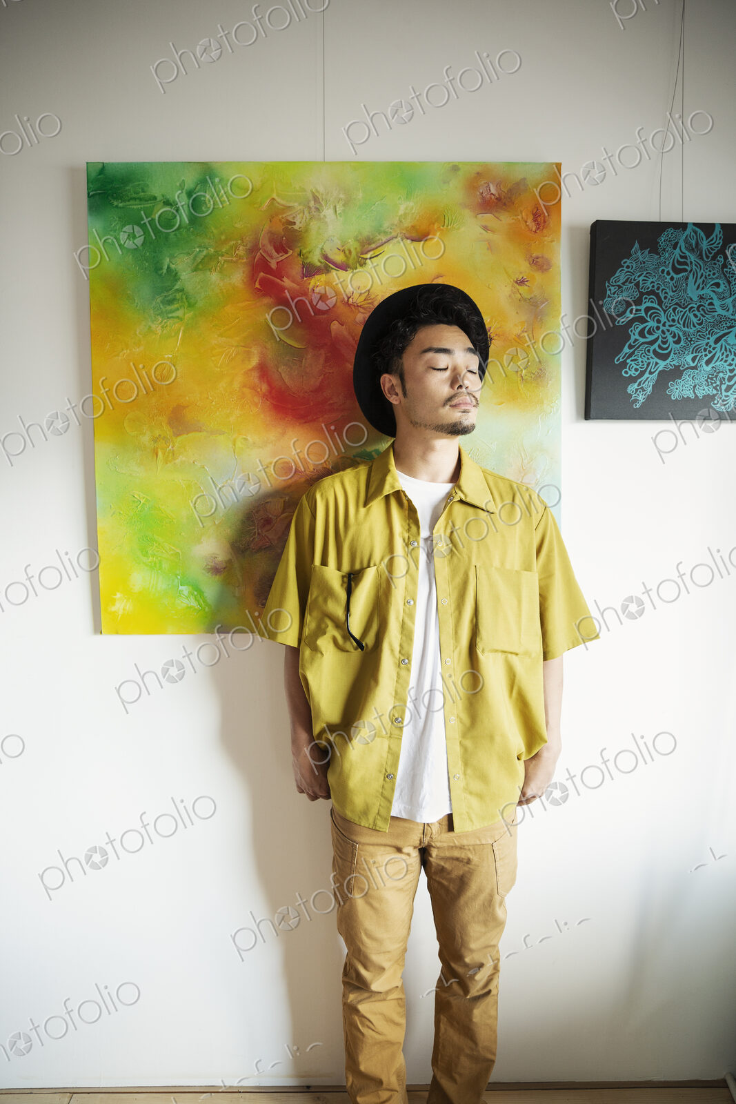 Japanese man standing in front of abstract painting in an art gallery.