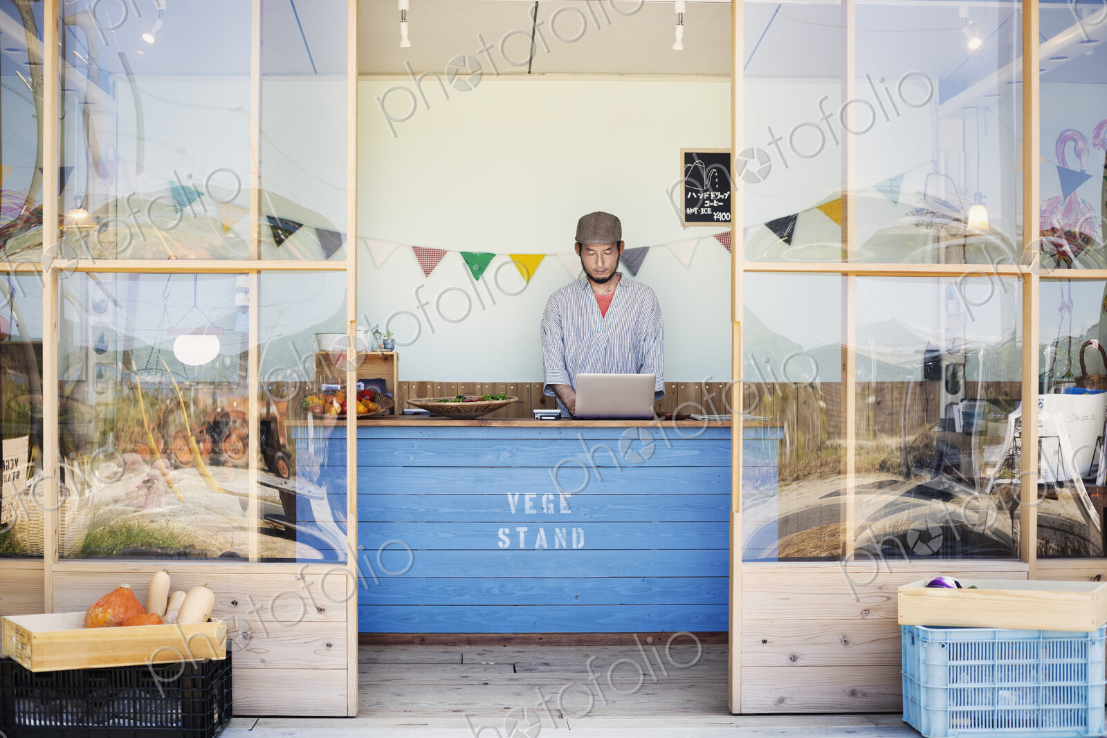 Japanese man wearing cap standing behind counter in farm shop.