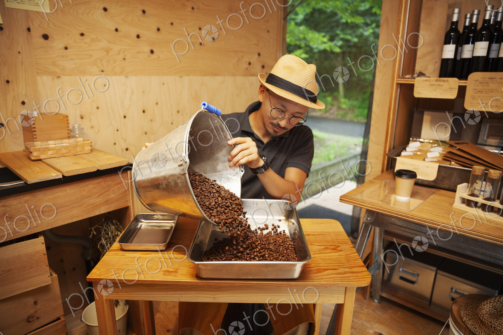 Japanese man wearing hat and glasses sitting in an Eco Cafe, pouring freshly roasted…