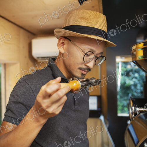 Japanese man wearing hat and glasses standing in an Eco Cafe, smelling freshly roasted… Japanese man wearing hat and glasses standing in an Eco Cafe, smelling freshly roasted…