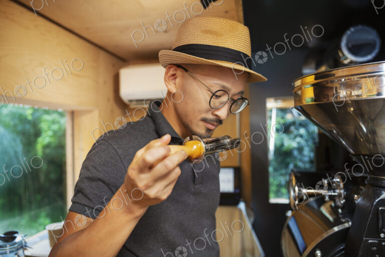 Japanese man wearing hat and glasses standing in an Eco Cafe, smelling freshly roasted…