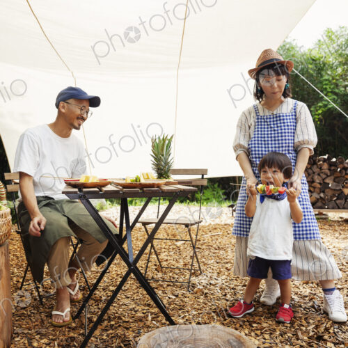 Japanese man, woman and boy gathered around a table under a canopy, preparing vegetables. Japanese man, woman and boy gathered around a table under a canopy, preparing vegetables.
