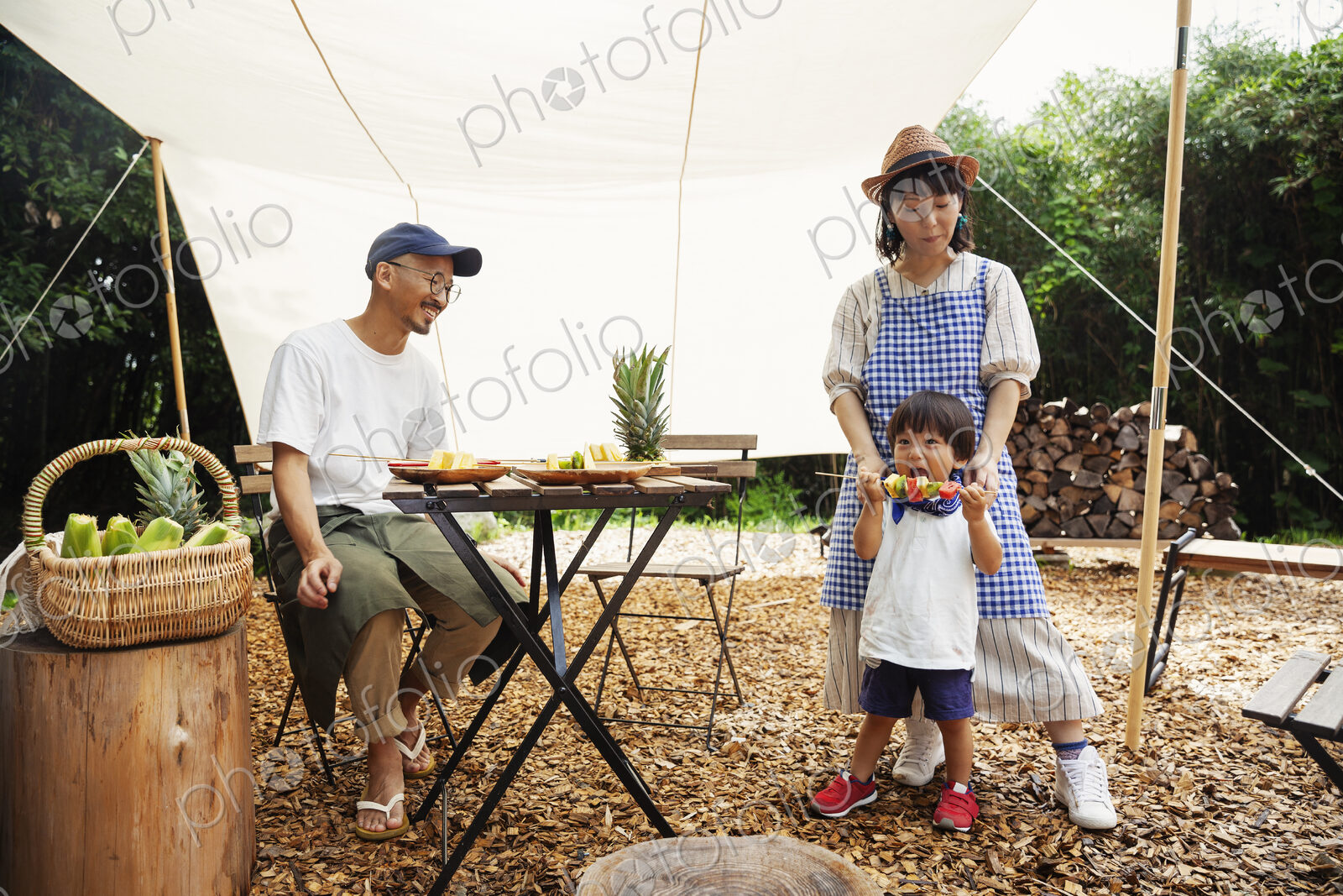 Japanese man, woman and boy gathered around a table under a canopy, preparing vegetables.