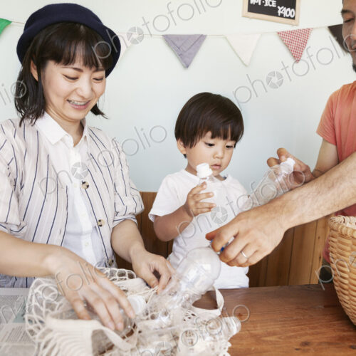 Japanese man, woman and boy standing in a farm shop, sorting clear plastic bottles…