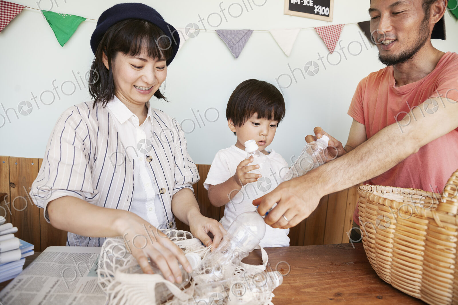 Japanese man, woman and boy standing in a farm shop, sorting clear plastic bottles…