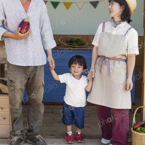 Japanese man, woman and boy standing outside a farm shop, holding hands. Japanese man, woman and boy standing outside a farm shop, holding hands.
