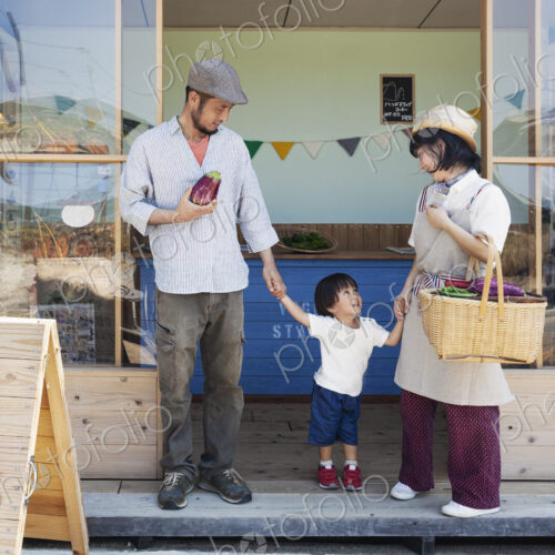 Japanese man, woman and boy standing outside a farm shop, holding hands. Japanese man, woman and boy standing outside a farm shop, holding hands.