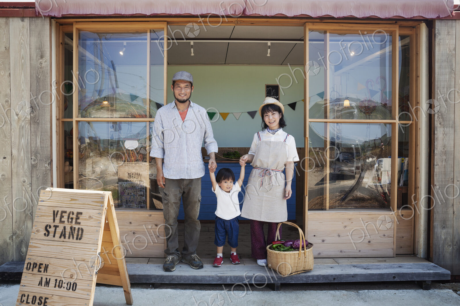 Japanese man, woman and boy standing outside a farm shop, holding hands, looking at…