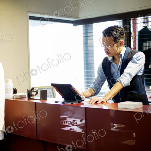 Japanese salesman with moustache wearing glasses standing at counter in clothing… Japanese salesman with moustache wearing glasses standing at counter in clothing…