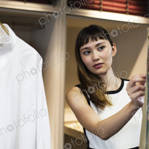 Japanese saleswoman standing in clothing store, looking at shirt. Japanese saleswoman standing in clothing store, looking at shirt.