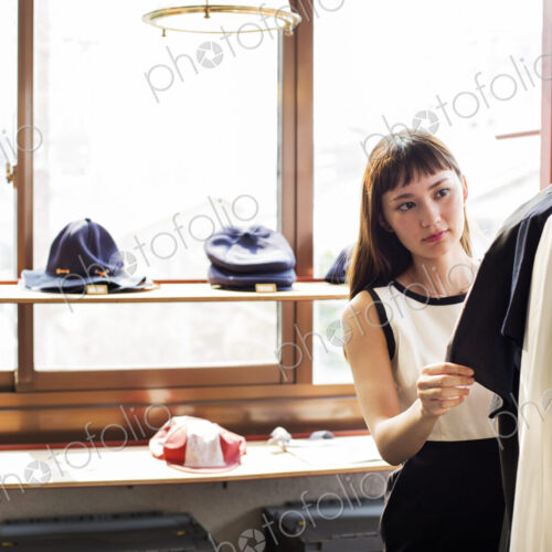Japanese saleswoman standing in clothing store, looking at shirt. Japanese saleswoman standing in clothing store, looking at shirt.