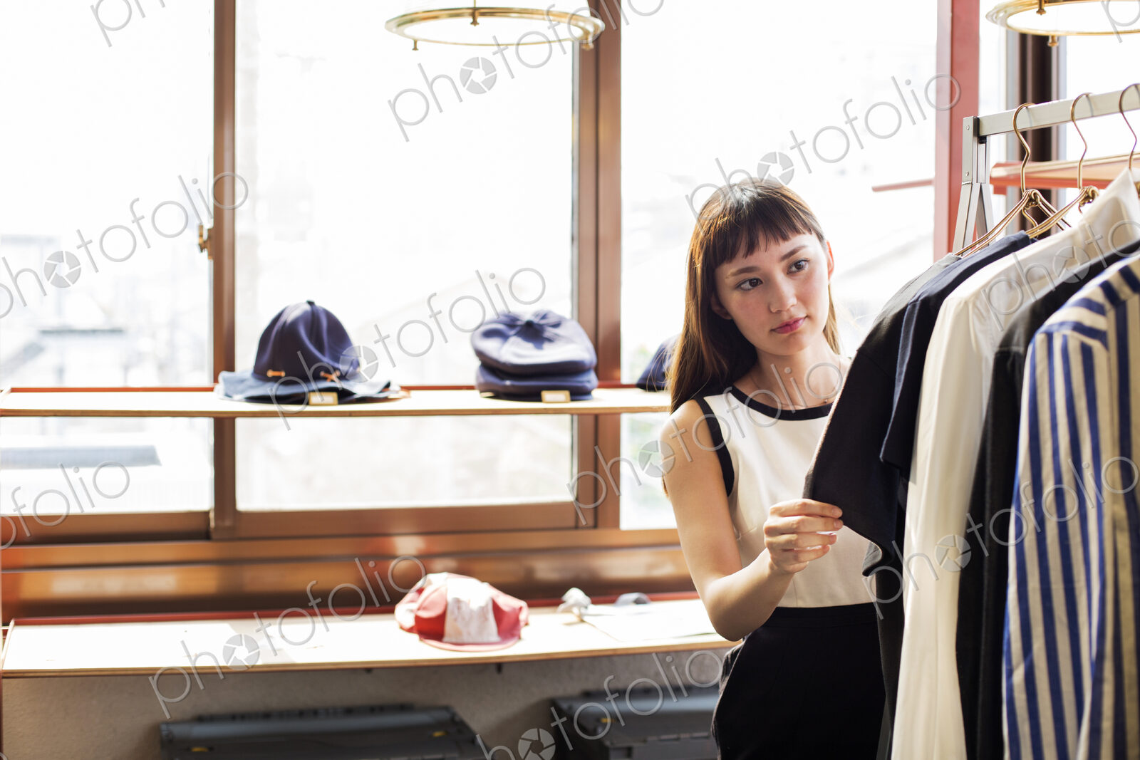 Japanese saleswoman standing in clothing store, looking at shirt.