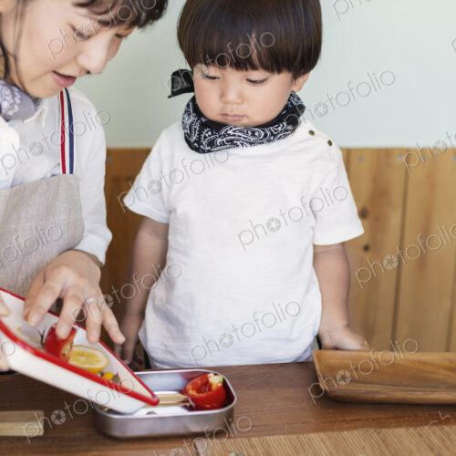 Japanese woman and boy standing in a farm shop, preparing food. Japanese woman and boy standing in a farm shop, preparing food.