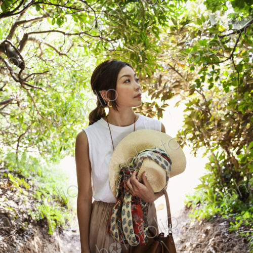 Japanese woman carrying hat hiking in a forest. Japanese woman carrying hat hiking in a forest.
