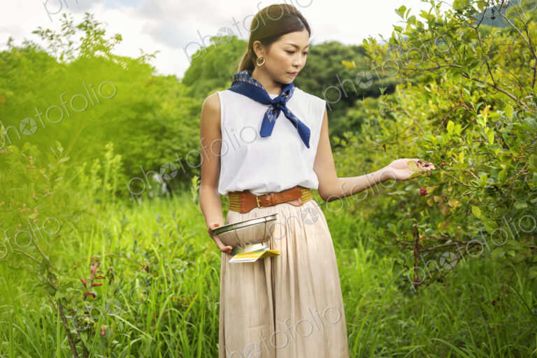 Japanese woman picking berries in a field.