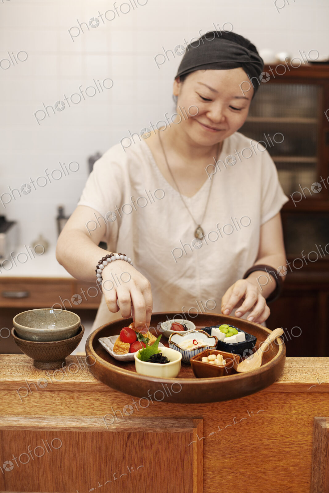 Japanese woman preparing fresh vegetables in a vegetarian cafe.