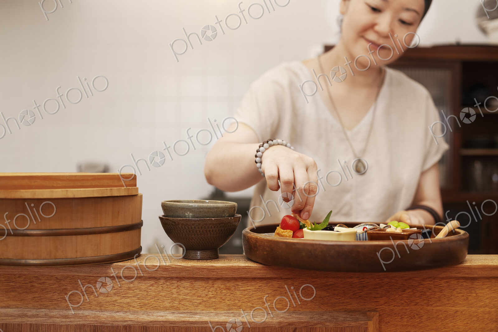 Japanese woman preparing fresh vegetables in a vegetarian cafe.