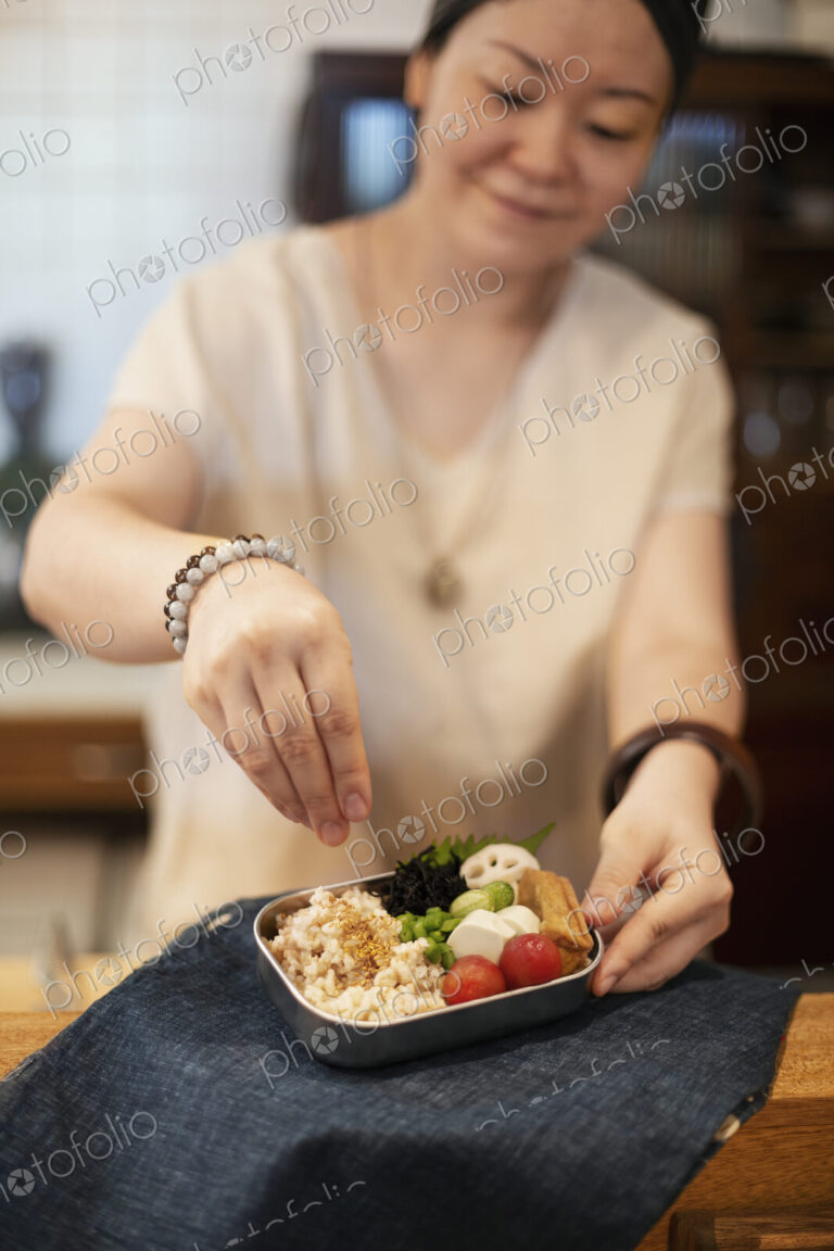 Japanese woman preparing fresh vegetables in a vegetarian cafe.