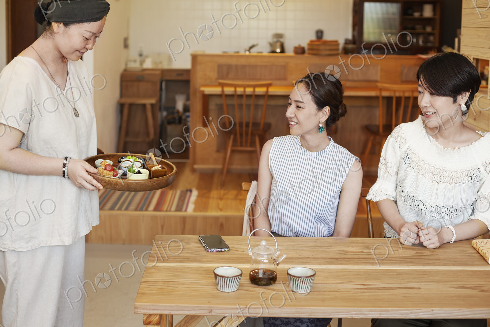 Japanese woman serving two female customers in a vegetarian cafe.