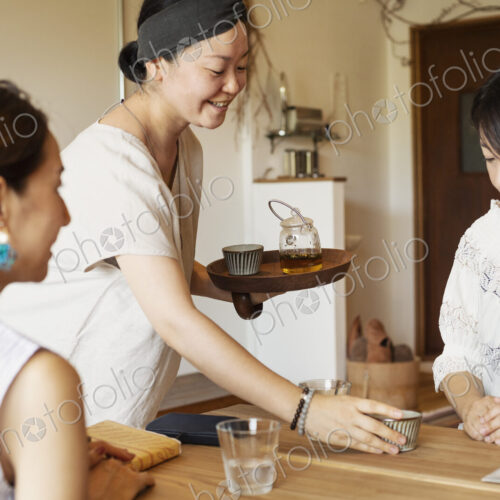 Japanese woman serving two female customers in a vegetarian cafe. Japanese woman serving two female customers in a vegetarian cafe.