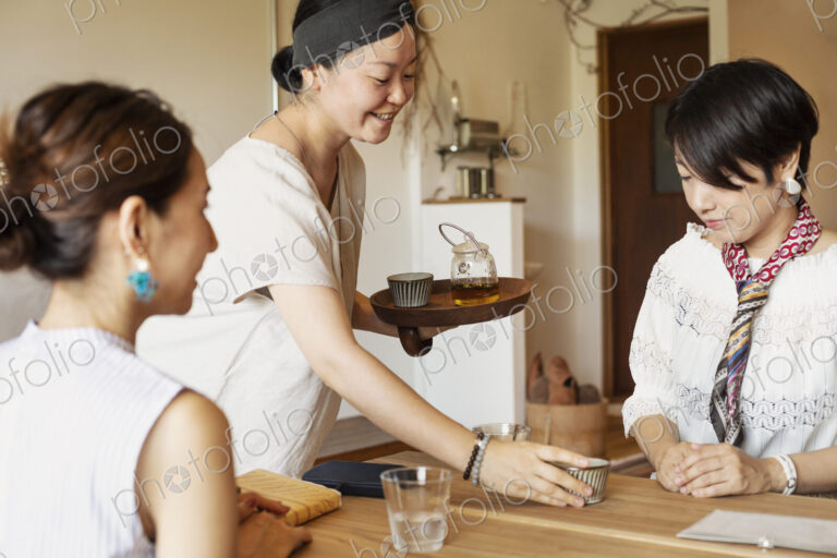 Japanese woman serving two female customers in a vegetarian cafe.