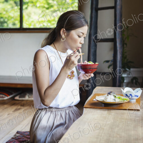 Japanese woman sitting at a table in a Japanese restaurant, eating. Japanese woman sitting at a table in a Japanese restaurant, eating.