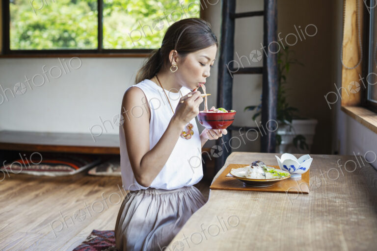 Japanese woman sitting at a table in a Japanese restaurant, eating.