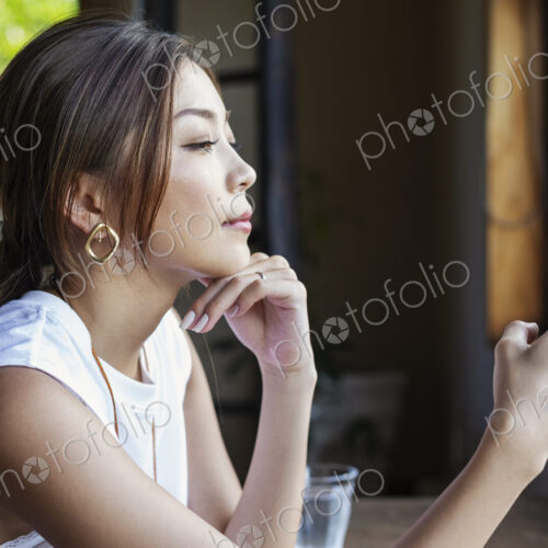 Japanese woman sitting at a table in a Japanese restaurant, using mobile phone. Japanese woman sitting at a table in a Japanese restaurant, using mobile phone.