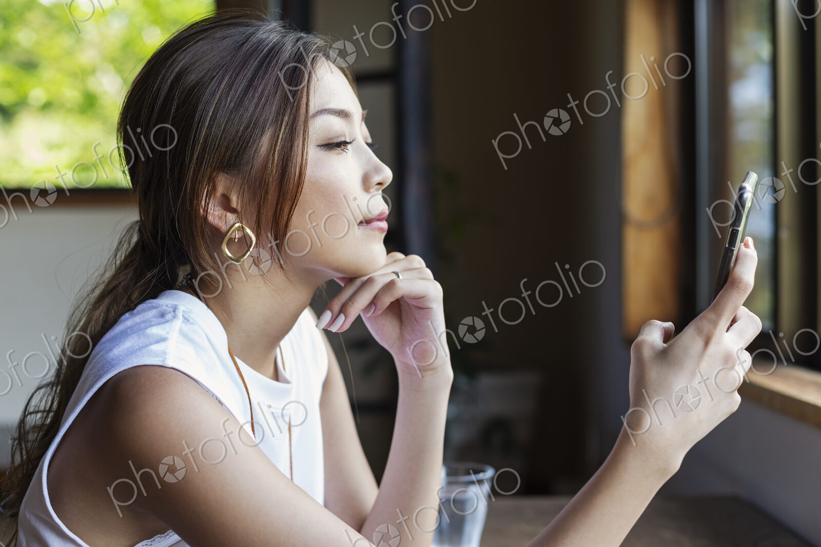 Japanese woman sitting at a table in a Japanese restaurant, using mobile phone.