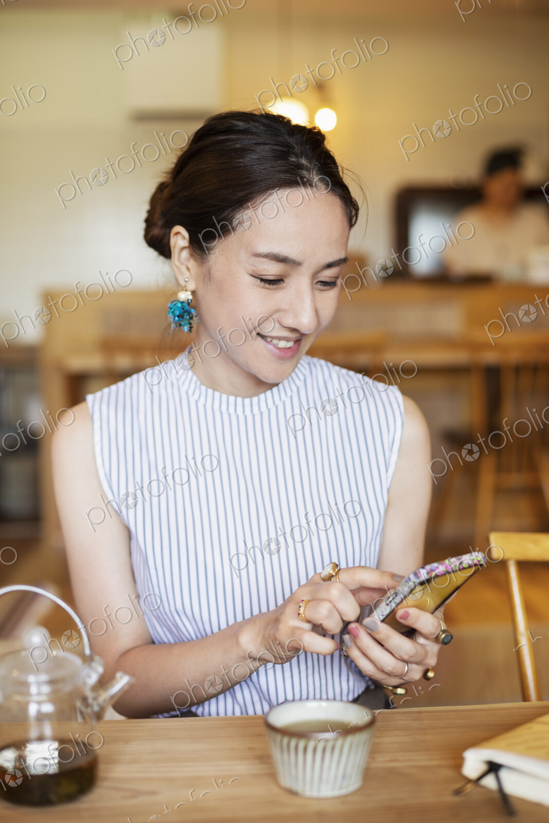 Japanese woman sitting at a table in a vegetarian cafe, using mobile phone.