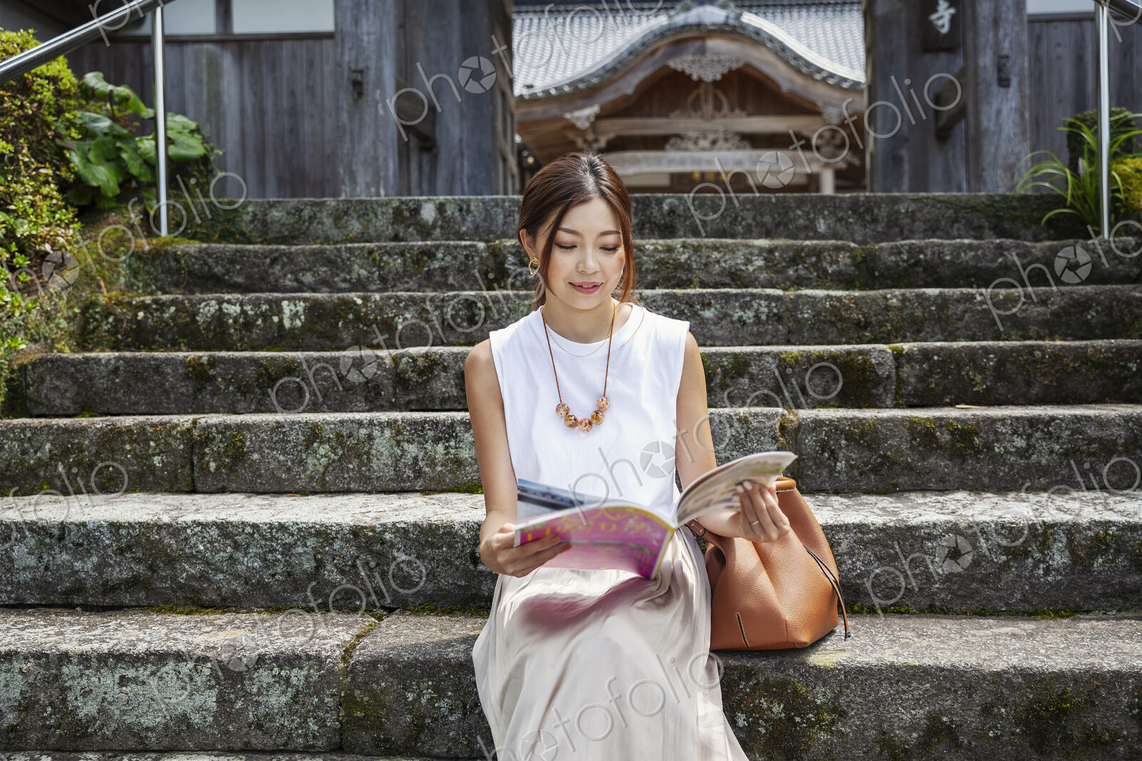 Japanese woman sitting on steps outside a Buddhist temple.