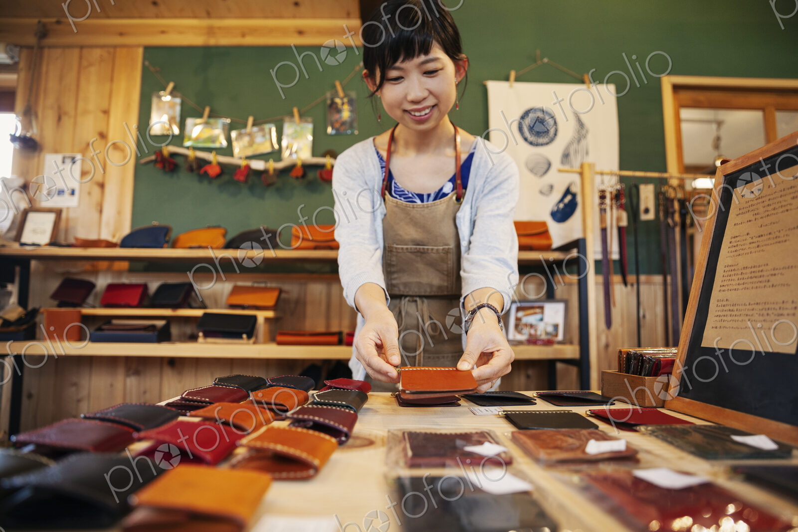 Japanese woman standing at a table, working in a leather shop.