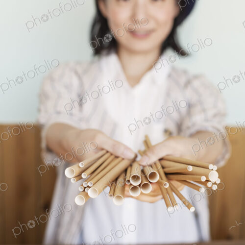 Japanese woman standing behind counter in a farm shop, holding bunch of cardboard rolls. Japanese woman standing behind counter in a farm shop, holding bunch of cardboard rolls.
