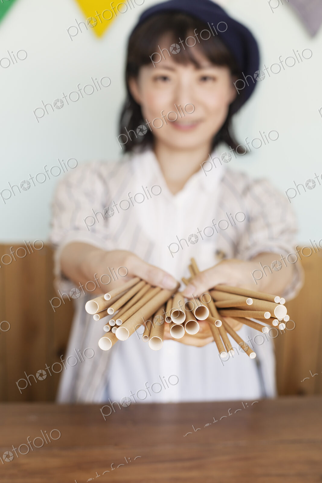 Japanese woman standing behind counter in a farm shop, holding bunch of cardboard rolls.
