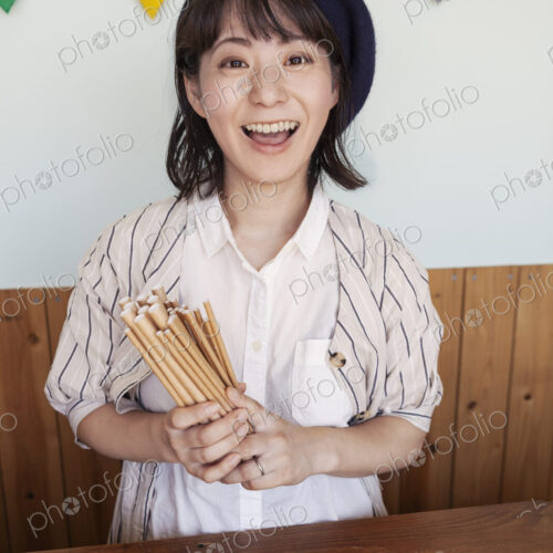 Japanese woman standing behind counter in a farm shop, smiling at camera.