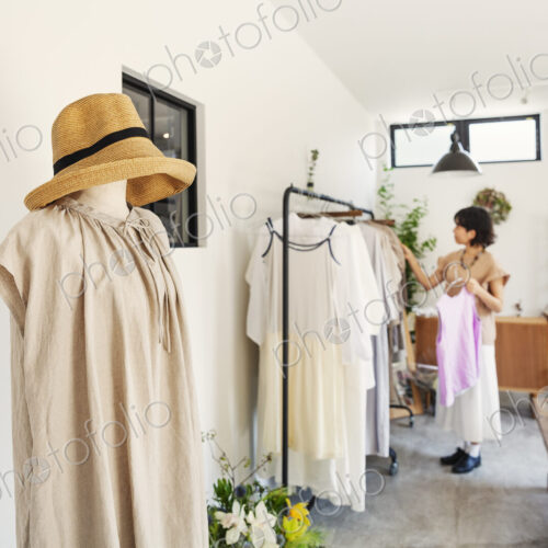 Japanese woman standing in a boutique, looking at clothes on a rail.