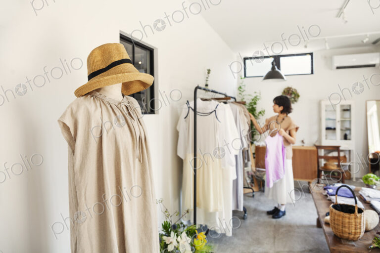 Japanese woman standing in a boutique, looking at clothes on a rail.
