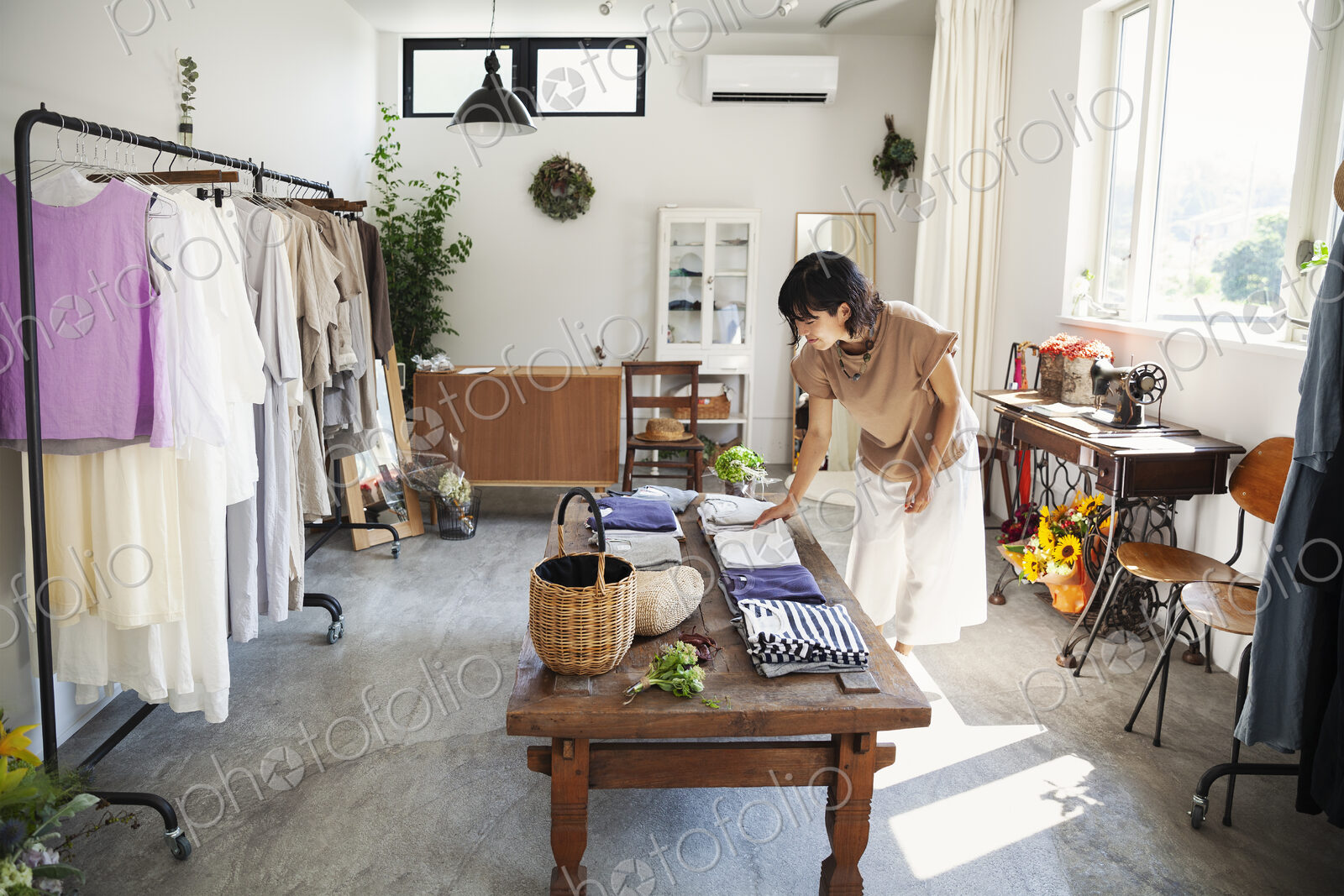 Japanese woman standing in a small fashion boutique, looking at T-Shirts on a coffee…