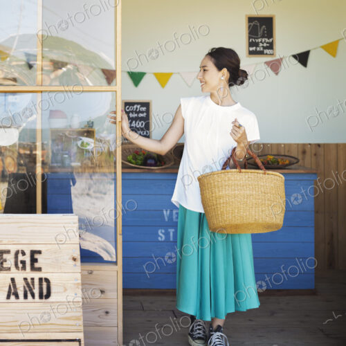 Japanese woman standing outside a farm shop, holding shopping bag. Japanese woman standing outside a farm shop, holding shopping bag.