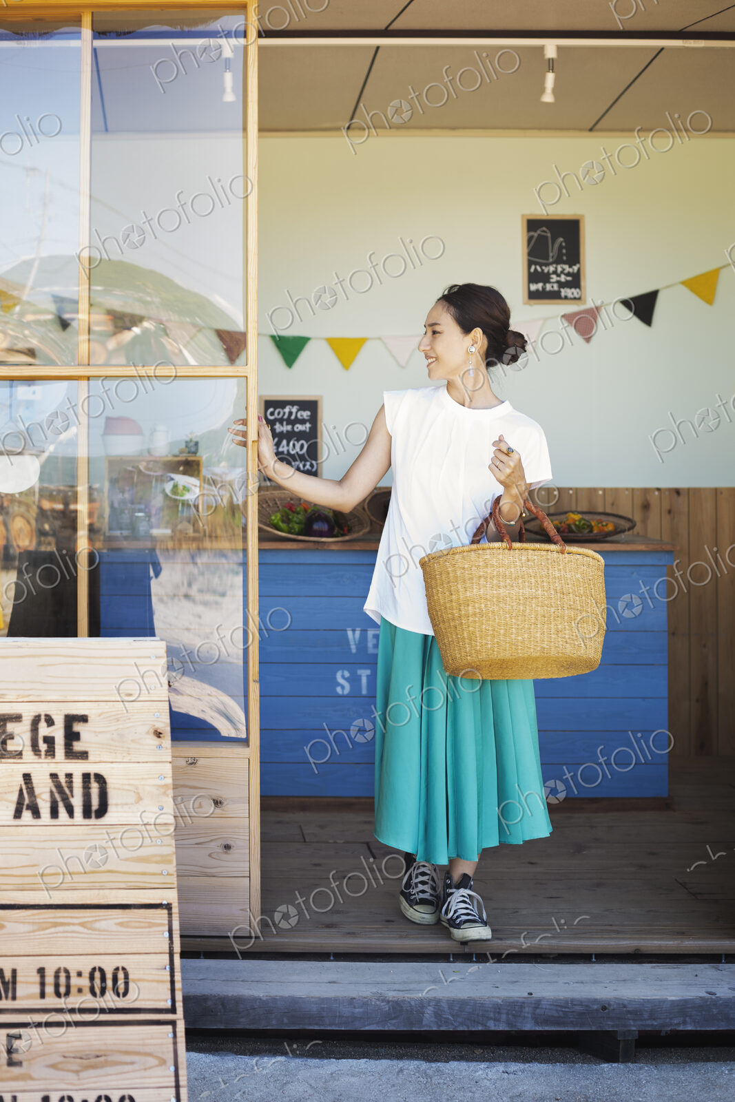 Japanese woman standing outside a farm shop, holding shopping bag.