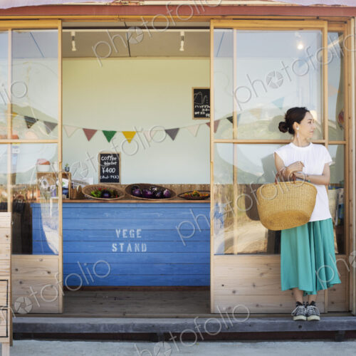Japanese woman standing outside a farm shop, holding shopping bag. Japanese woman standing outside a farm shop, holding shopping bag.