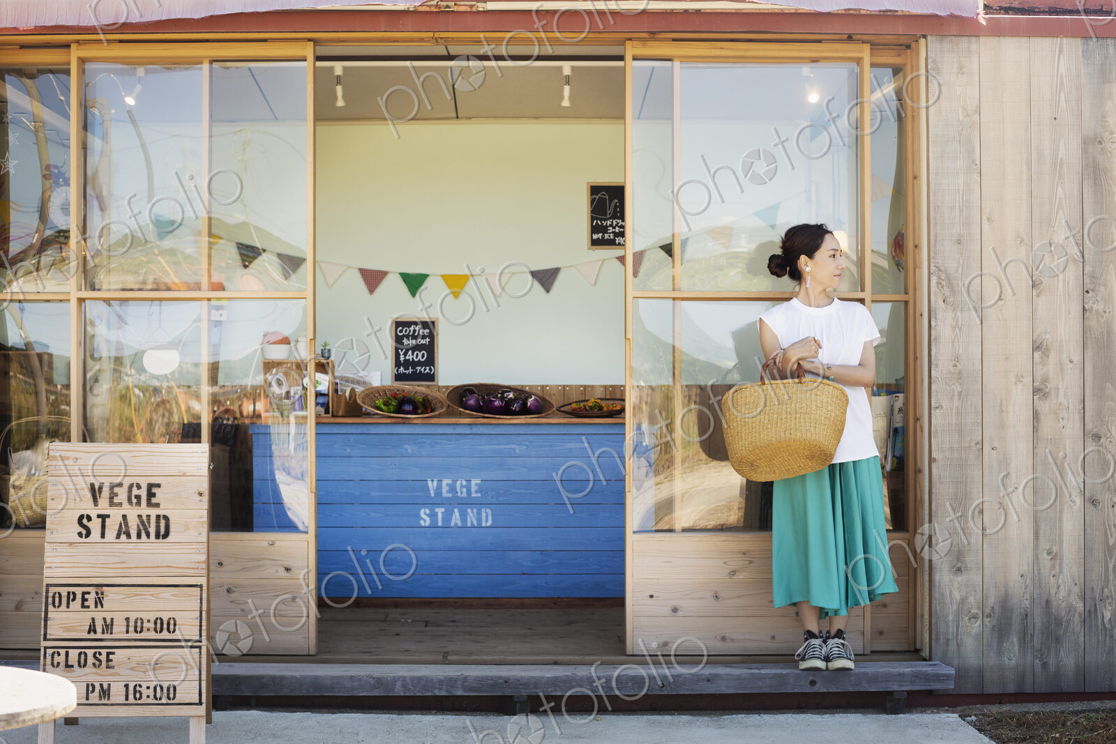 Japanese woman standing outside a farm shop, holding shopping bag.