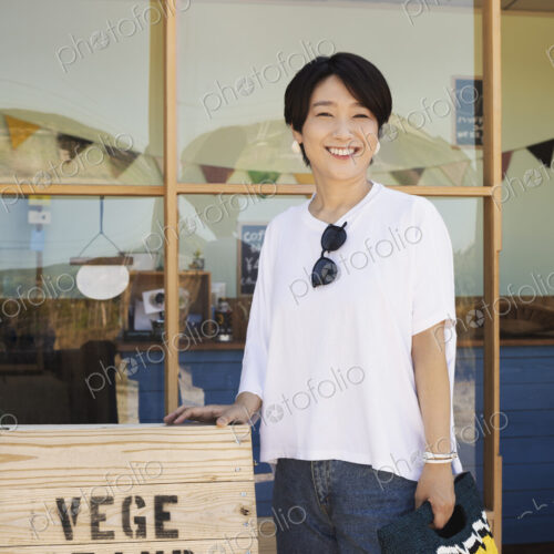 Japanese woman standing outside a farm shop, holding shopping bag, smiling at camera. Japanese woman standing outside a farm shop, holding shopping bag, smiling at camera.