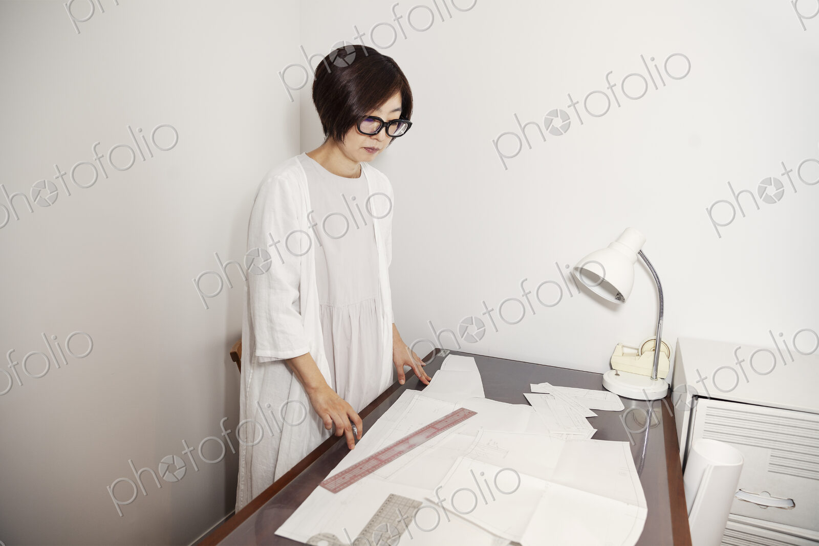Japanese woman wearing glasses working at a desk in a small fashion boutique.
