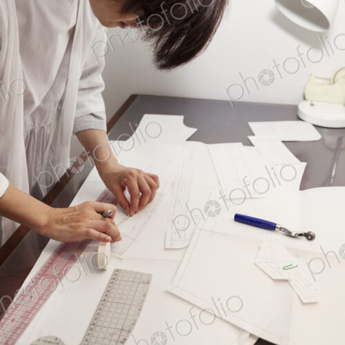 Japanese woman wearing glasses working at a desk in a small fashion boutique.