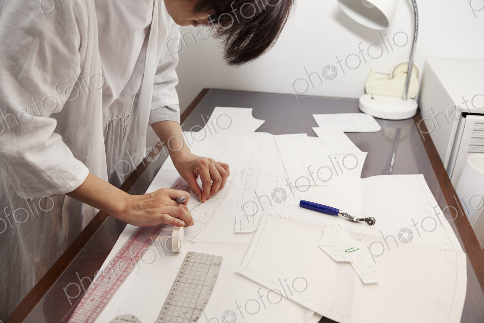 Japanese woman wearing glasses working at a desk in a small fashion boutique.