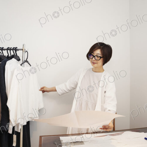 Japanese woman wearing glasses working at a desk in a small fashion boutique. Japanese woman wearing glasses working at a desk in a small fashion boutique.
