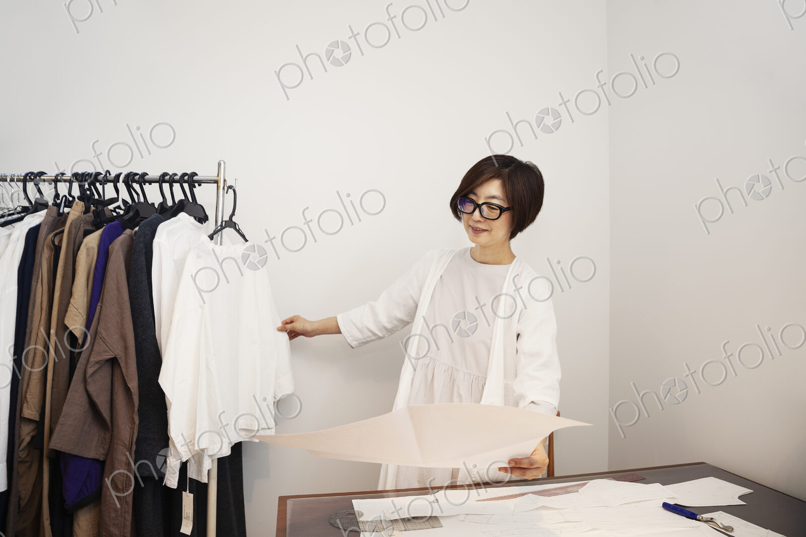 Japanese woman wearing glasses working at a desk in a small fashion boutique.