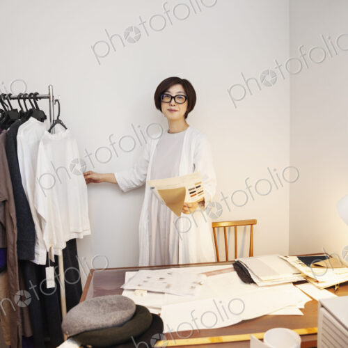 Japanese woman wearing glasses working at a desk in a small fashion boutique. Japanese woman wearing glasses working at a desk in a small fashion boutique.