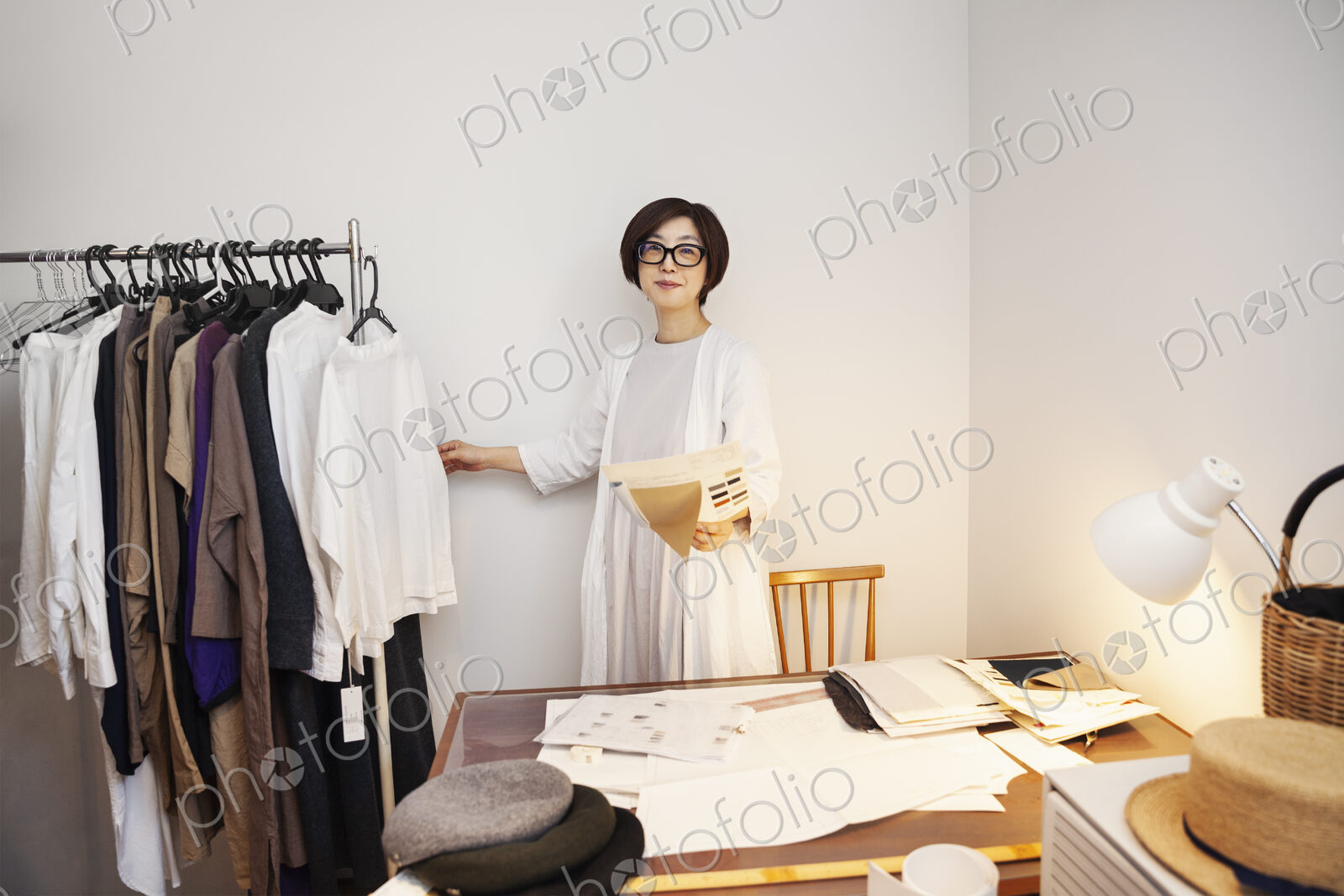 Japanese woman wearing glasses working at a desk in a small fashion boutique.